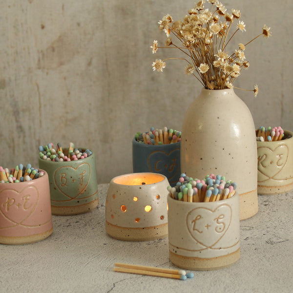 Personalised initial match pots in all pastel colours with lit tealight and vase of flowers