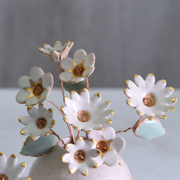 Decorative ceramic flowers with gold accents on a grey background