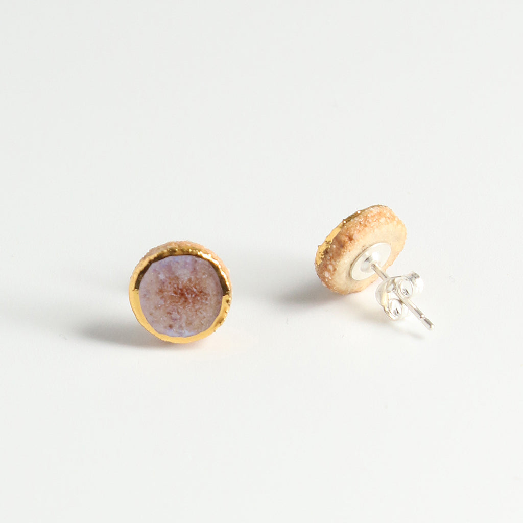 Pair of earrings with gold and pink finishes on a light grey background