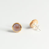 Pair of earrings with gold and pink finishes on a light grey background