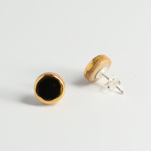 Gold earrings with black a centre on a light grey background