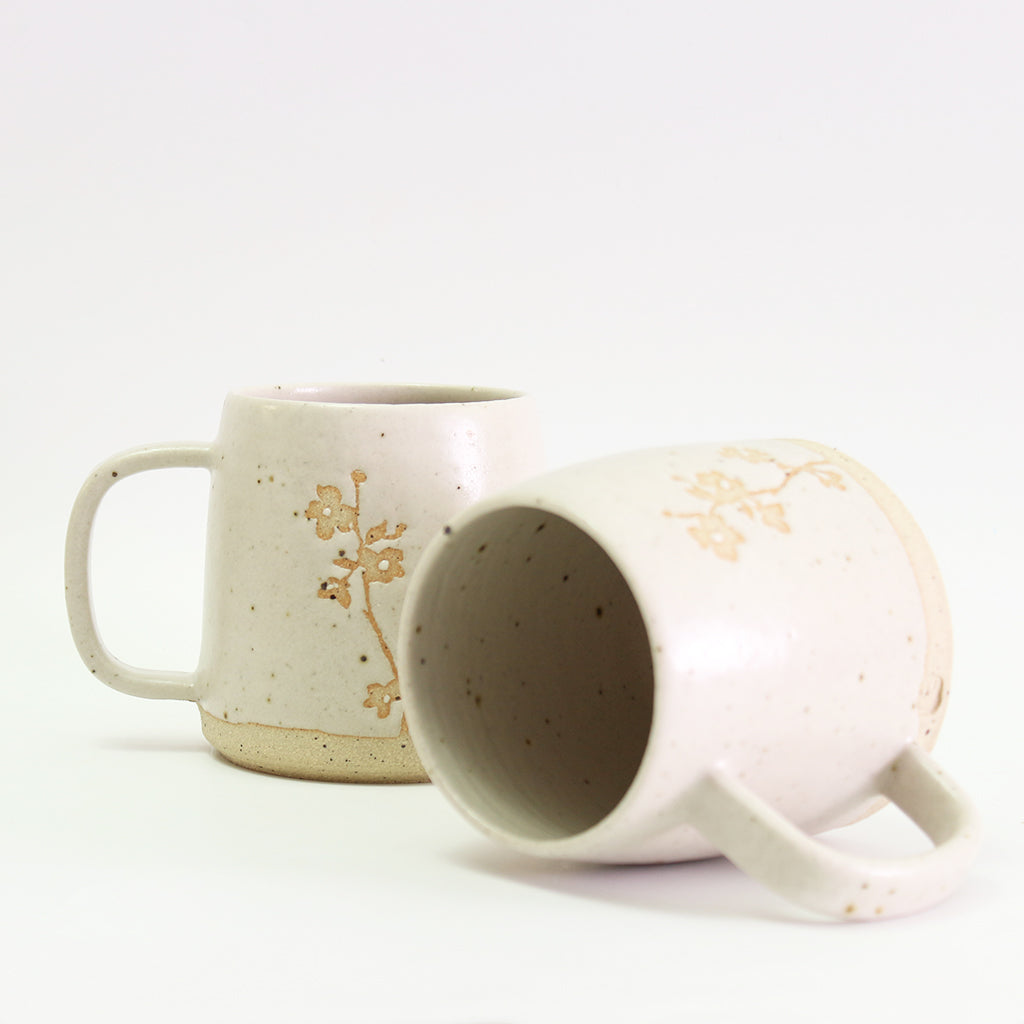 Two Cherry Blossom mugs, one on its side