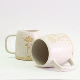 Two Cosmos mugs, one on its side