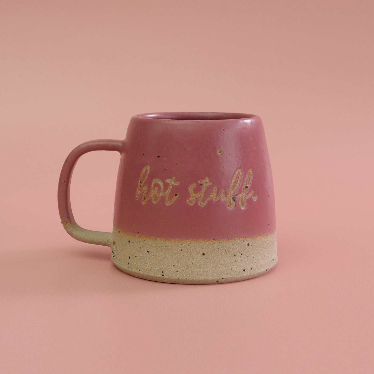 Pink mug with 'hot stuff' text on a pink background. The mug is made from a fleck stoneware by habulous ceramics 