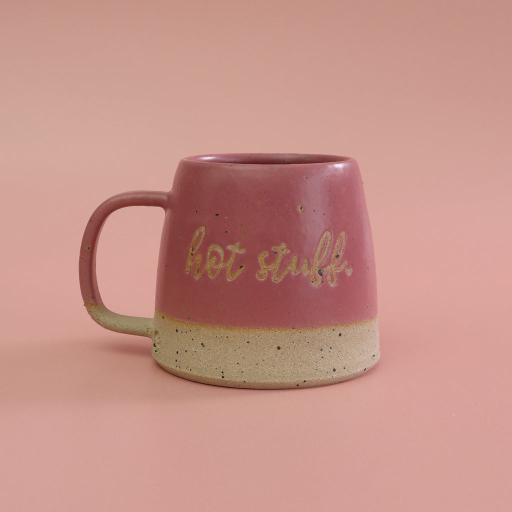 Pink mug with 'hot stuff' text on a pink background. The mug is made from a fleck stoneware by habulous ceramics 