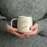 Hands holding Honeysuckle birth flower mug
