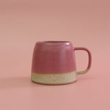 Pink ceramic mug with a beige base on a pink background