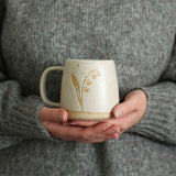 Hands holding Lily of the Valley mug