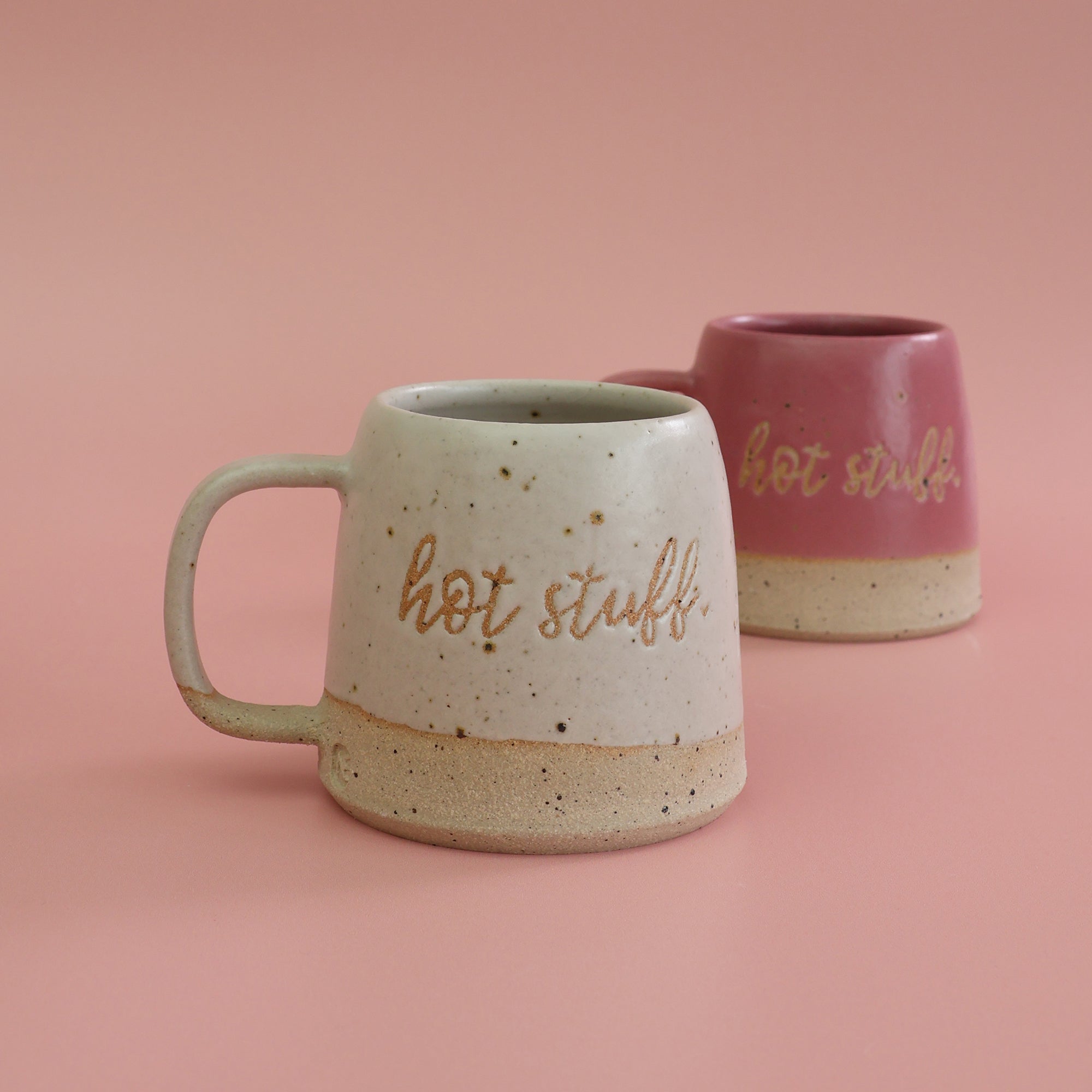 Two ceramic mugs with 'hot stuff' text on a pink background