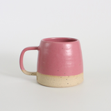 fuchsia ceramic mug with a beige base on a light gray background