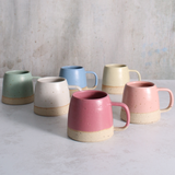 Set of colorful ceramic mugs on a light gray surface with a neutral background