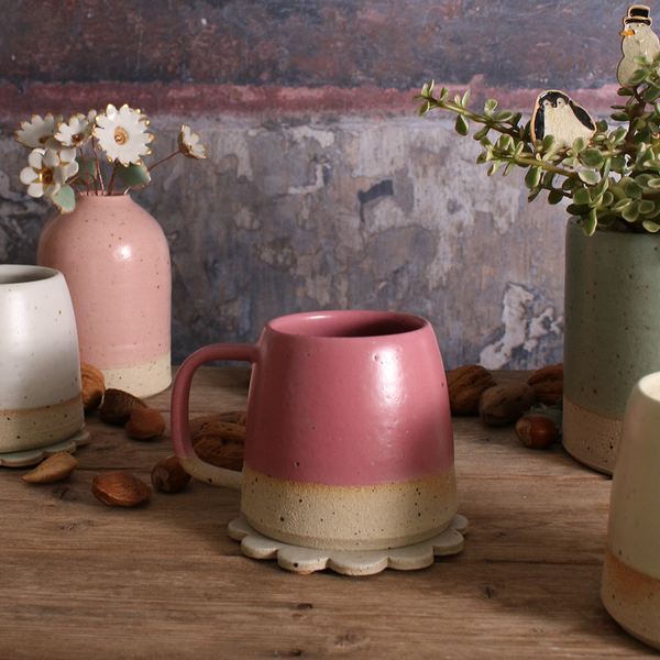 Pink ceramic mug on a wooden surface with decorative elements
