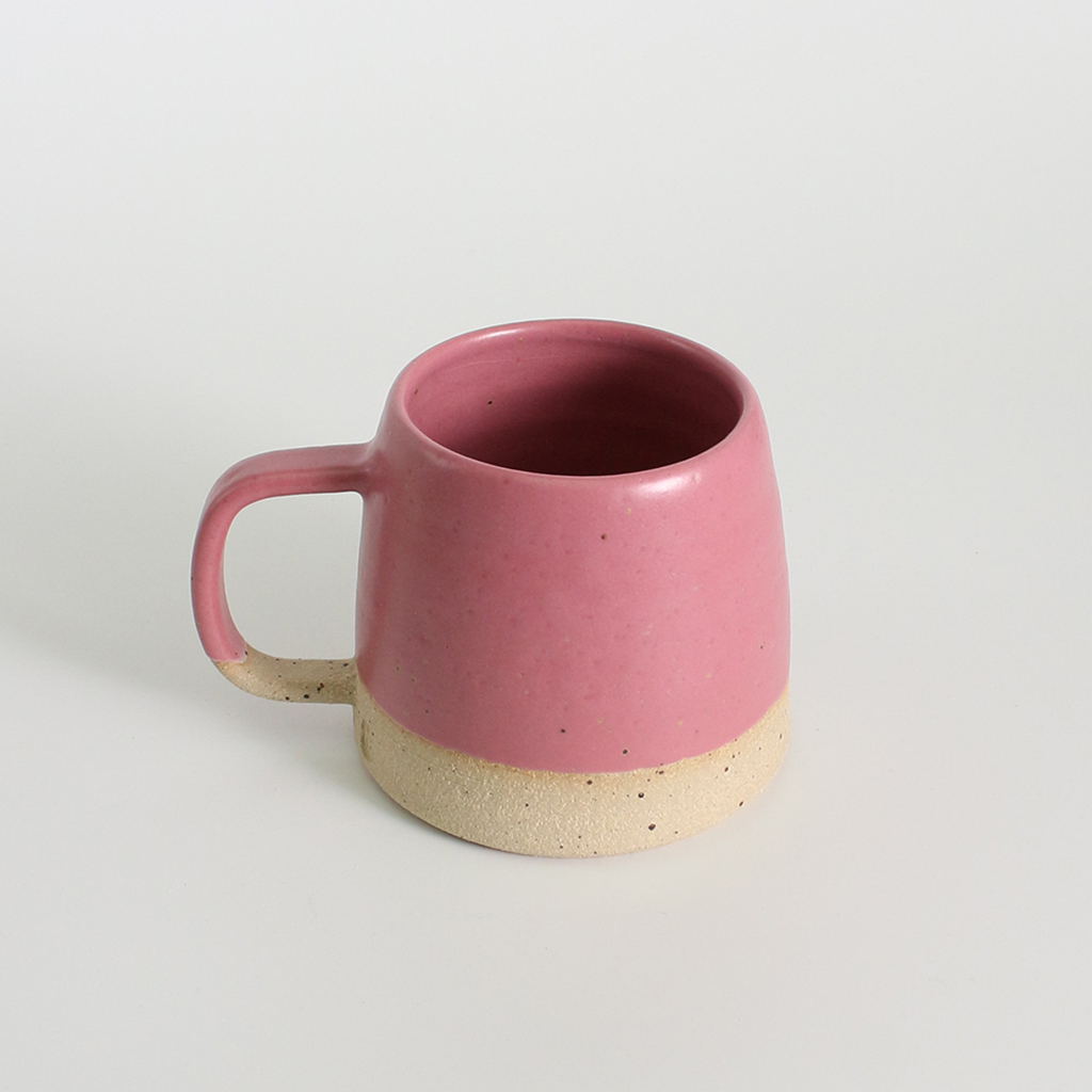 Pink ceramic mug with a beige base on a light grey background