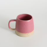 Pink ceramic mug with a beige base on a light grey background