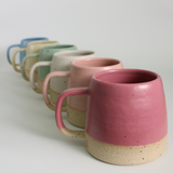 Row of ceramic mugs with various pastel colors on a light background