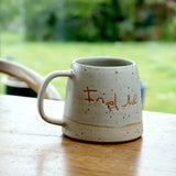 Custom handwriting ceramic mug on a wooden table. The mug is customised with the name 'Indie'