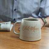 Handmade ceramic mug personalised with the words old man. the mug is on a wooden table