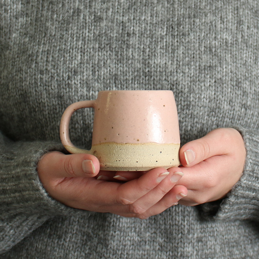 Hands holding pale pink small mug