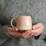 Hands holding pale pink small mug