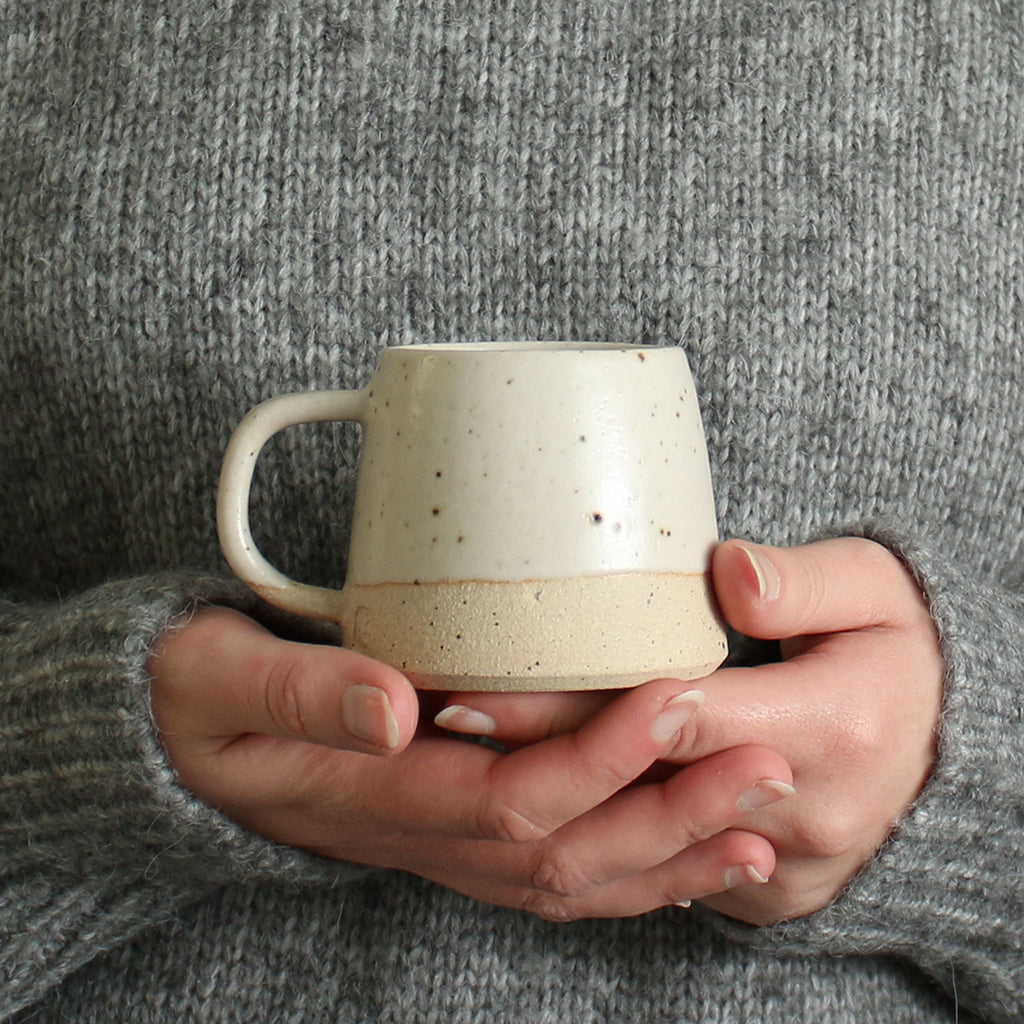 Hands holding off-white mug