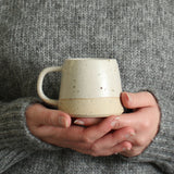 Hands holding off-white mug