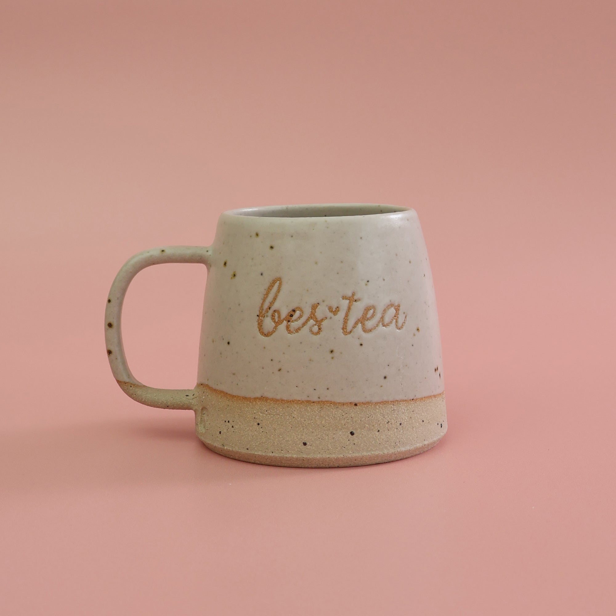 Speckled ceramic mug with 'bestea' text on a pink background