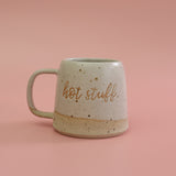 Speckled ceramic stoneware mug with 'hot stuff' text on a pink background. The mug is handmade by Habulous Ceramics 