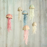 cluster of 6 ceramic jellyfish in blue, green, pink, a pale pink and white hang in front of a textured grey background  the jellyfish are handmade in the UK by Habulous Ceramics 