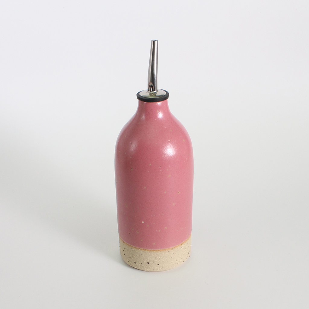 Pink ceramic oil pourer bottle with a metal nozzle on a white background
