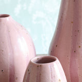 Close-up of three pink striped ceramic vases, arranged closely together. 