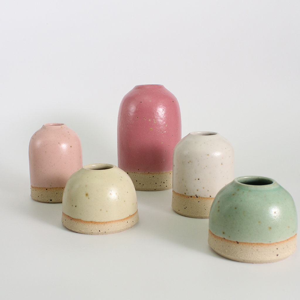 Set of five ceramic vases in pastel colors on a white background