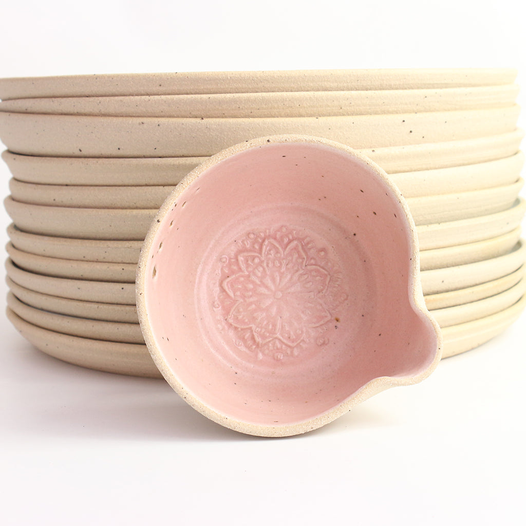 Pink herb bowl propped up against stack of dinner plates