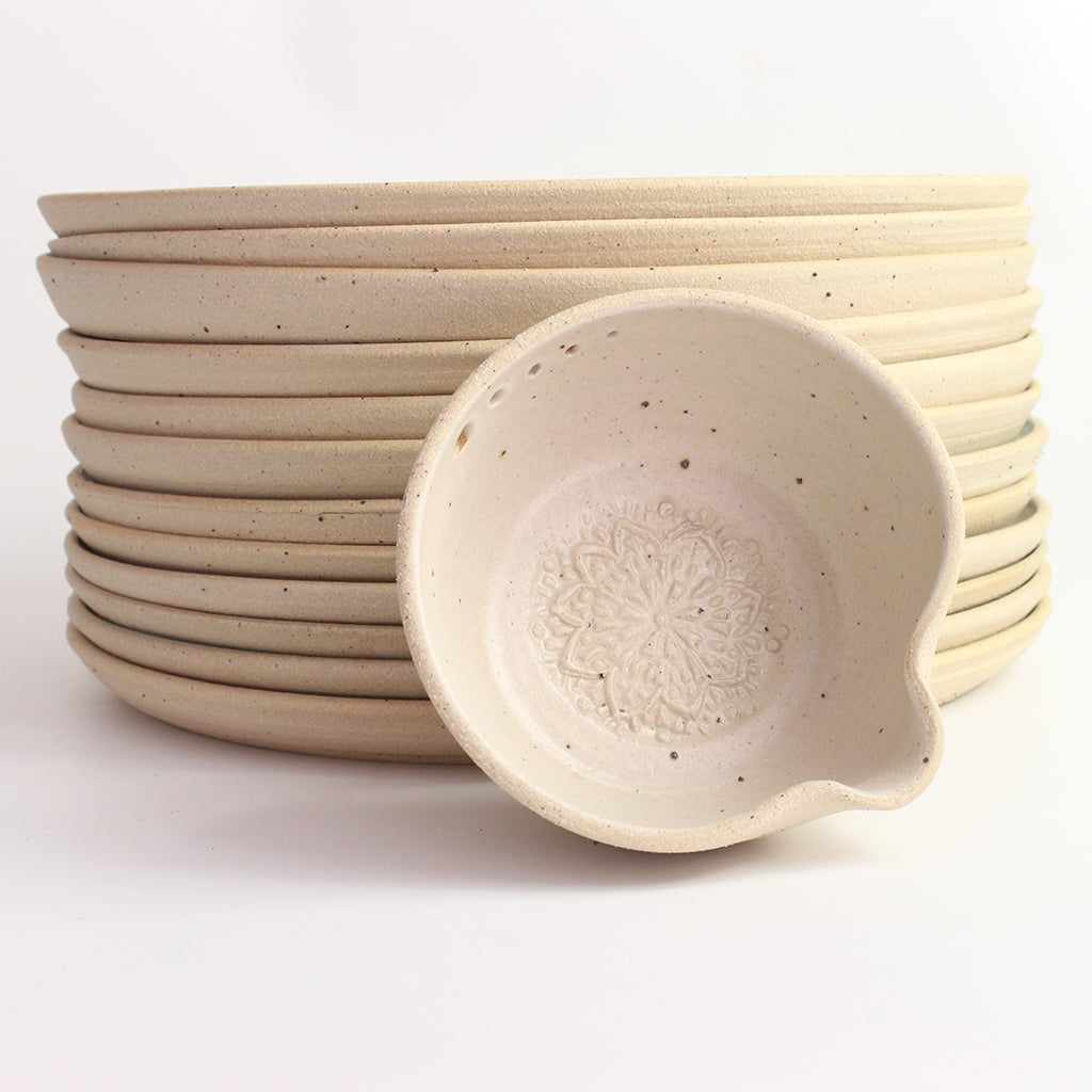 White herb bowl propped against stack of dinner plates