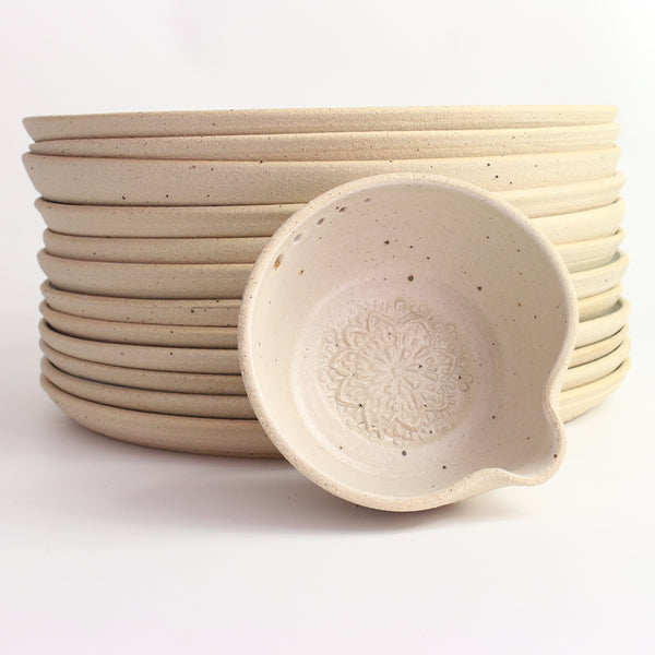 White herb bowl propped against stack of dinner plates