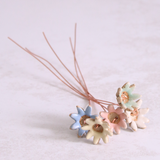 Close-up of hand holding pastel ceramic daisy flower stems with copper wire stems – individually handcrafted floral home accessories from Habulous