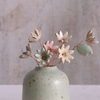 Pastel ceramic daisy flower stems displayed in a handcrafted green speckled vase – artisan home décor by Habulous