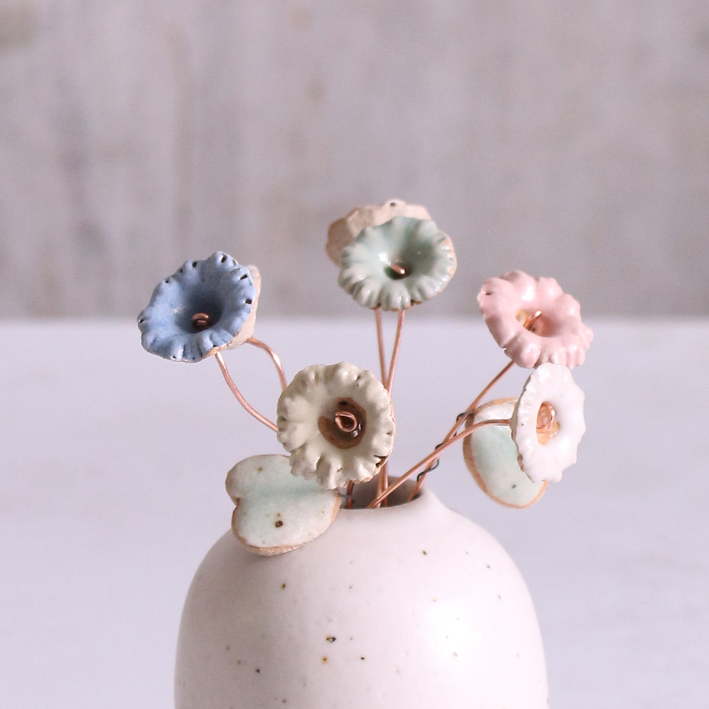 Handcrafted ceramic wildflower stems in various pastel colours, displayed in a minimalist off-white vase. Each flower features a flexible copper wire stem for easy arrangement.