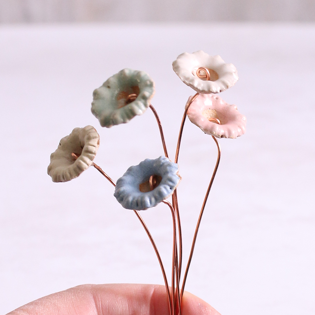 Close-up of hand holding pastel ceramic wild flower stems with copper wire stems – individually handcrafted floral home accessories from Habulous