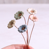 Close-up of hand holding pastel ceramic wild flower stems with copper wire stems – individually handcrafted floral home accessories from Habulous
