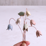 Close-up of hand holding pastel ceramic flower stems with copper wire stems – individually handcrafted floral home accessories from Habulous