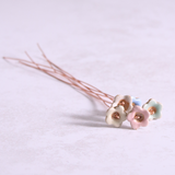 Close-up of table with pastel ceramic flower stems with copper wire stems lay on it – individually handcrafted floral home accessories from Habulous