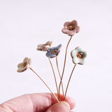 Close-up of hand holding pastel ceramic flower stems with copper wire stems – individually handcrafted floral home accessories from Habulous