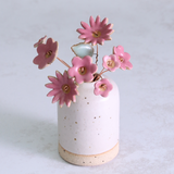 White ceramic vase with pink floral decorations on a light gray background