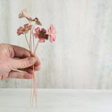 ceramic flowers on copper wires held in a female hand - ceramic flowers handmade by Habulous Ceramics 