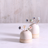 Pastel blue ceramic forget me not flower stems displayed across two handcrafted speckled vases– artisan home décor by Habulous