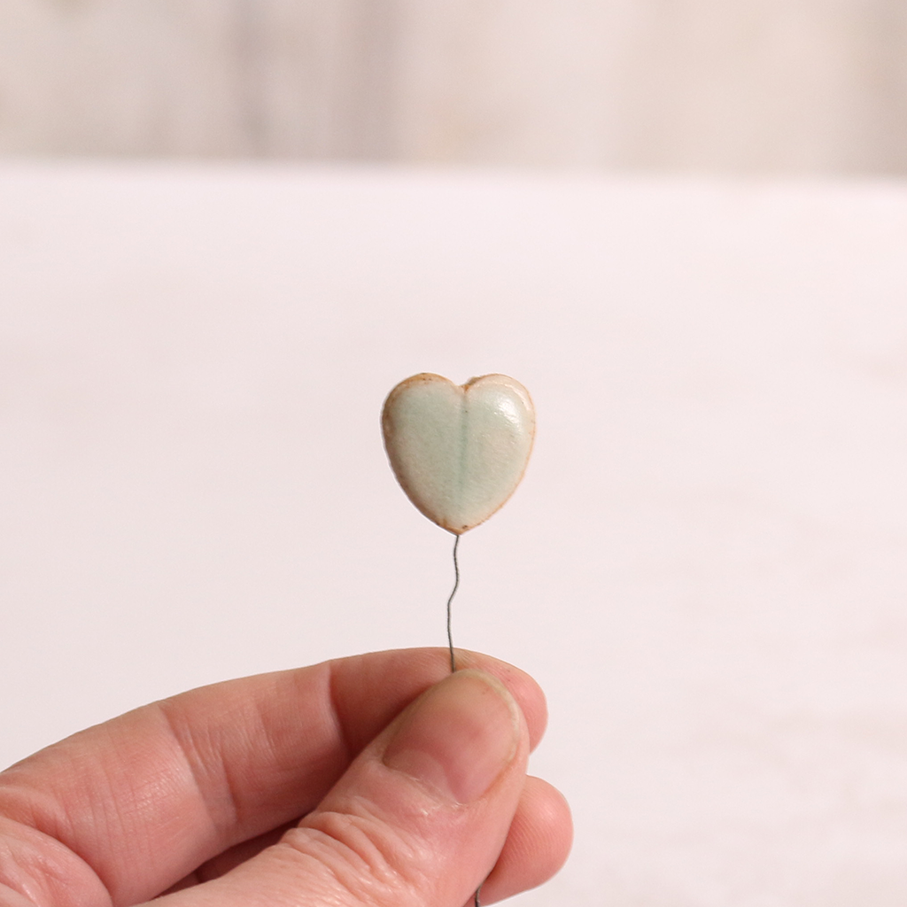 Close up of heart-shaped ceramic leaf being held in someone's hands.