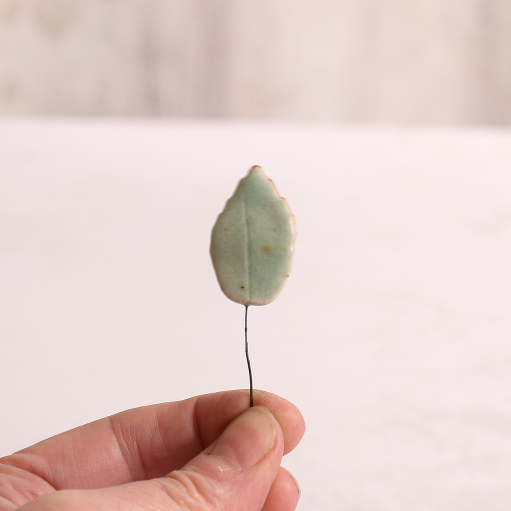 Close up of large ceramic leaf being held in someone's hands.