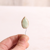 Close up of small ceramic leaf being held in someone's hands.