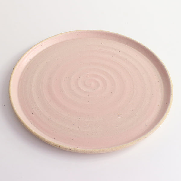 Above view of pink glazed and flecked stoneware of plate