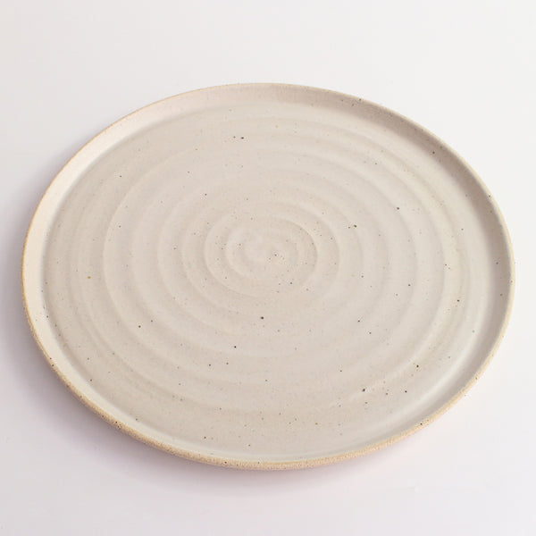 Above view of white glazed and flecked stoneware of plate
